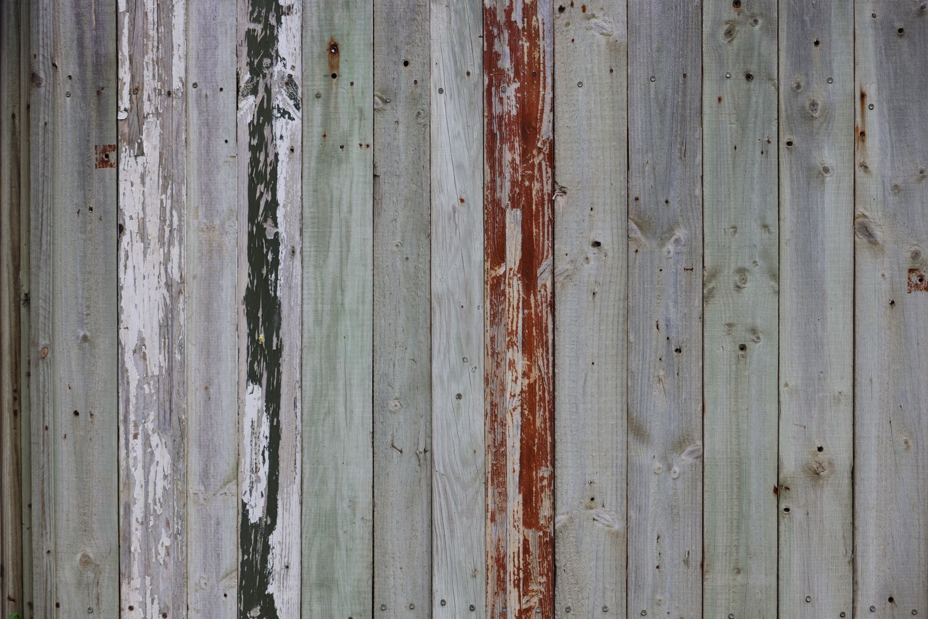 Wooden fence boards stacked on a sunny patio, showcasing natural grain and weathered pine texture.