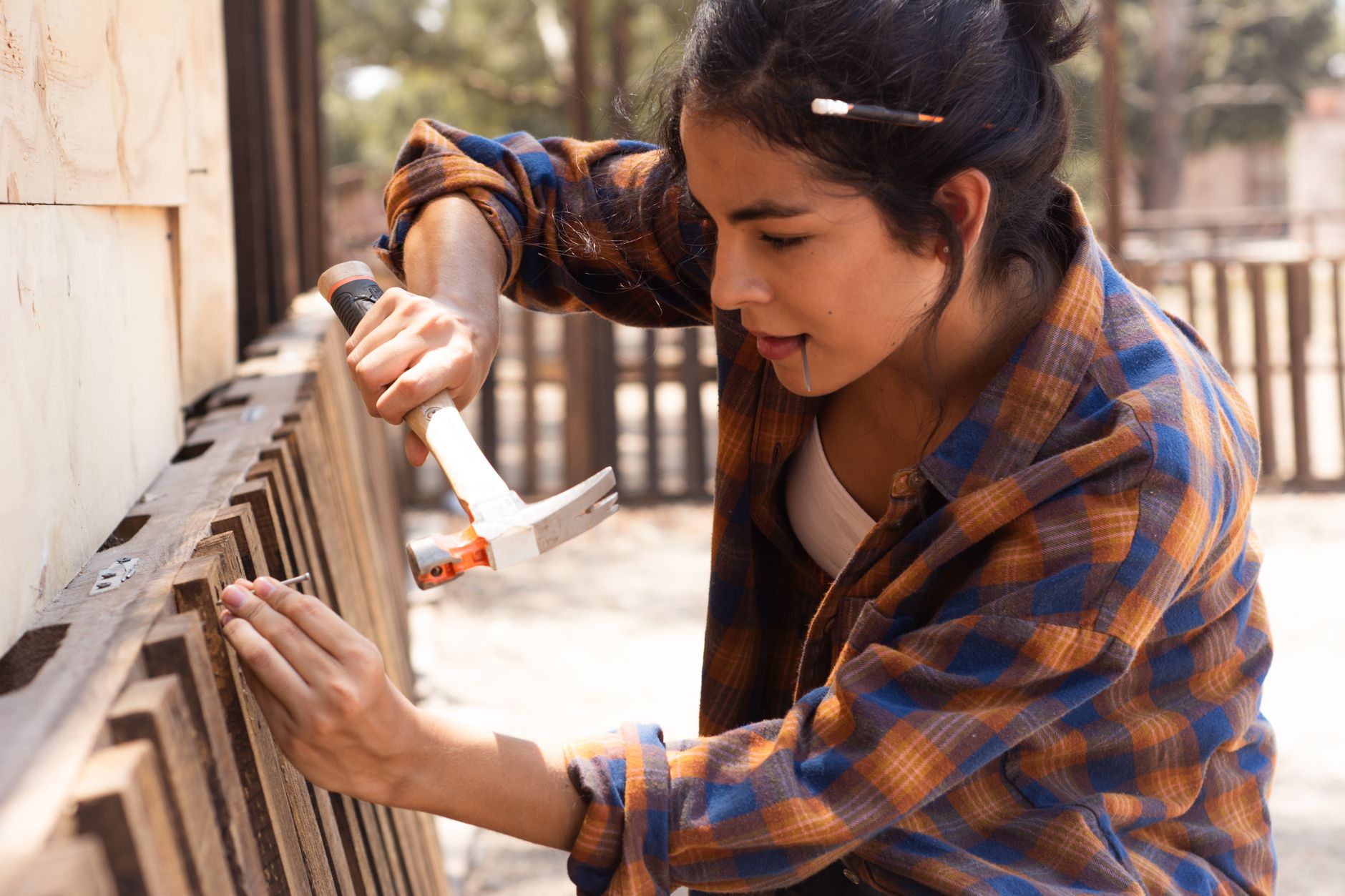 wooden-fence-repair-how-to-fix-8447789 A close-up of a carpenter replacing damaged slats on a wooden fence, tools and fresh lumber nearby.